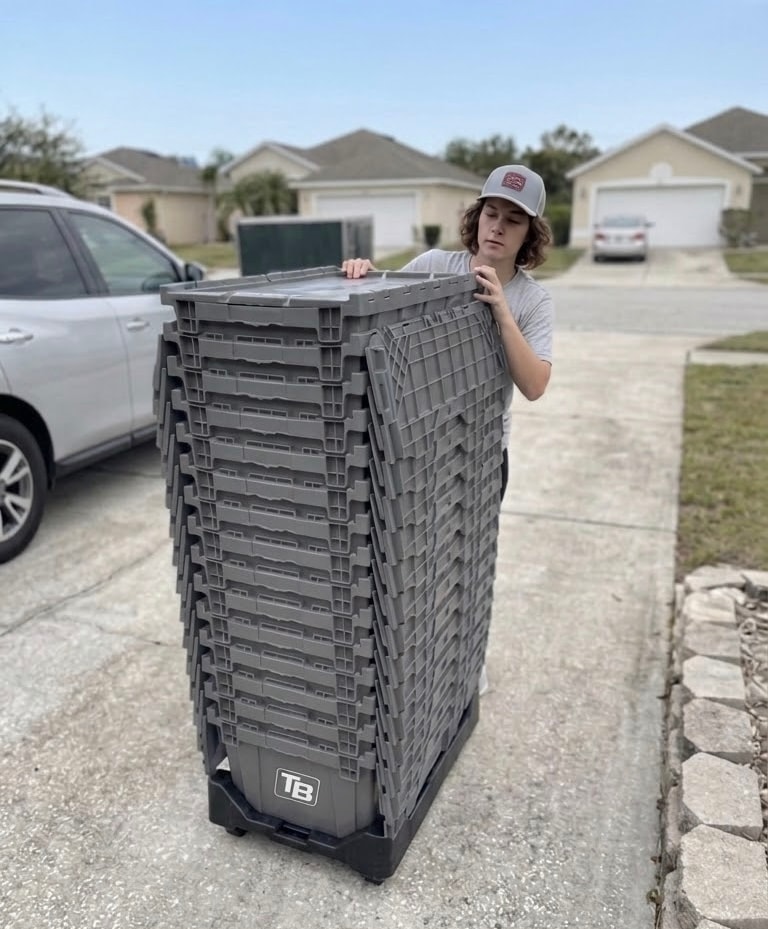 Tampa Bin Co team member rolling stack of TB bins on driveway