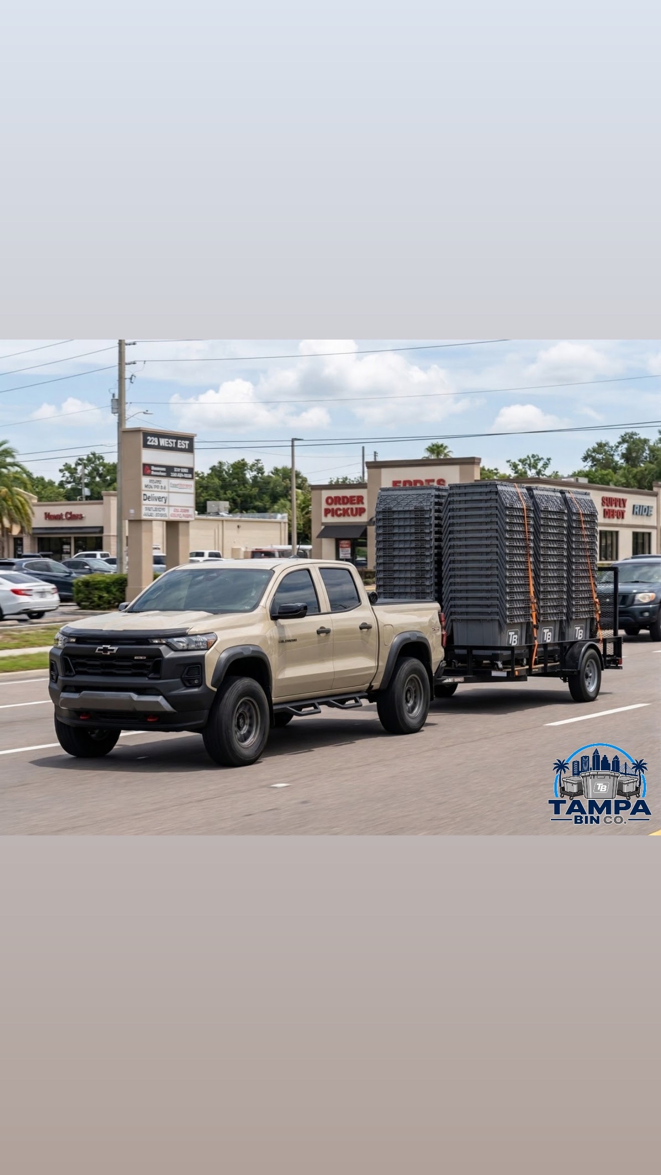 Tampa Bin Co Chevy truck hauling trailer loaded with TB bins through Tampa